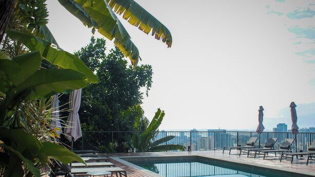 A poolside area with lounge chairs and umbrellas, surrounded by tropical foliage. - Boutique Hotel Castelinho (Rio de Janeiro)