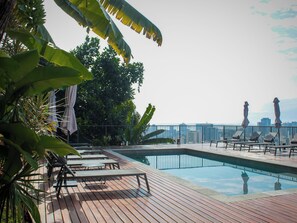 A poolside area with lounge chairs and umbrellas, surrounded by tropical foliage. - Boutique Hotel Castelinho (Rio de Janeiro)