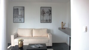 A modern living room with a beige sofa, a coffee table with a vase and a book, and two framed pictures on the wall. - Boutique Hotel Castelinho (Rio de Janeiro)