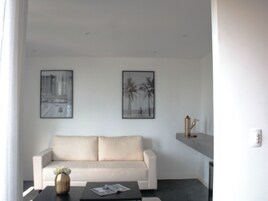 Ein modernes Wohnzimmer mit einem beigefarbenen Sofa, einem Couchtisch mit Vase und Buch sowie zwei gerahmten Bildern an der Wand.