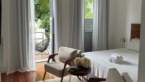 A bedroom with a bed, two chairs, a small table with flowers, and a hanging light fixture. - Boutique Hotel Castelinho (Rio de Janeiro)