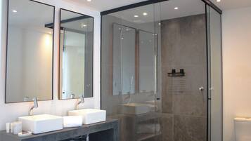 Een moderne badkamer met twee wasbakken, een douchecabine van glas en een toilet.