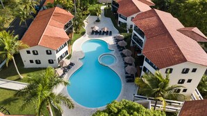 A resort with a central swimming pool, multiple lounge areas, and a well-maintained garden. - Luxury Apartment-Mandatory All-Inclusive (Puerto Plata)