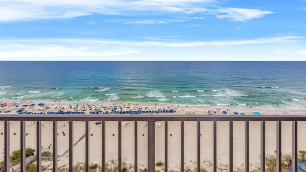 A beach with umbrellas and people, a clear sky, and the ocean. - The Summit 1503 (Panama City Beach)