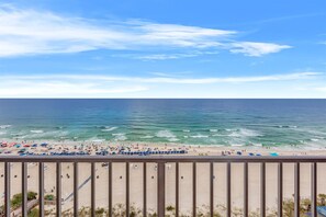 Uma praia com guarda-sóis e pessoas, céu claro e oceano.