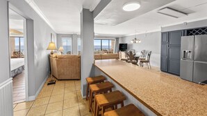 A modern kitchen with a granite countertop, wooden stools, and a built-in refrigerator. - The Summit 1503 (Panama City Beach)