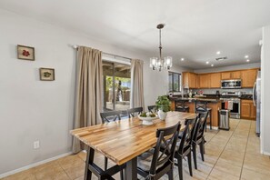 A modern kitchen with wooden cabinets, stainless steel appliances, and a dining area with a wooden table and chairs.