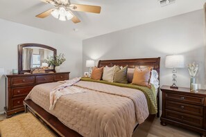 A bedroom with a bed, dresser, nightstands, a ceiling fan, and a mirror.