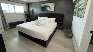 A modern bedroom with a large bed, a dark headboard, a wall-mounted air conditioner, and a window with curtains. - The Summit 1305 (Panama City Beach)