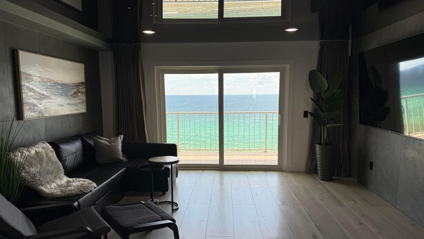 A spacious living area with a large sliding glass door leading to a balcony overlooking the sea. - The Summit 1305 (Panama City Beach)