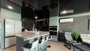A modern kitchen with a central island, bar stools, and a seating area with a sofa and chairs. - The Summit 1305 (Panama City Beach)