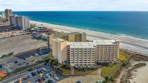 A beachfront hotel with multiple floors, a parking lot, and a view of the ocean. - Top of The Gulf 306 (Panama City Beach)