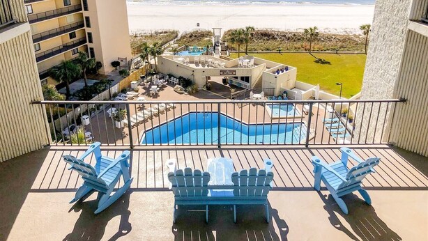 A balcony with a view of a beach and a pool area. - Top of The Gulf 306 (Panama City Beach)