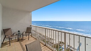 A balcony with a view of the ocean, featuring a table and chairs. - The Summit 1213 (Panama City Beach)