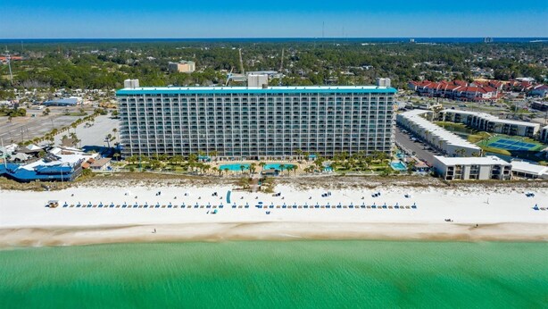 A large hotel with a central courtyard, multiple swimming pools, and a beach area with sun loungers. - The Summit 1213 (Panama City Beach)