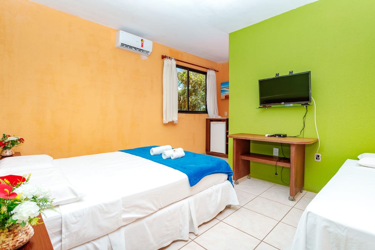 A hotel room with two beds, a TV, and a desk.