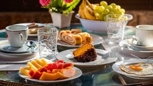 Desayuno con platos de comida, un bol de fruta y una taza de café.