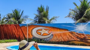 Una persona descansando junto a una piscina con un mural al fondo.