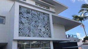Un edificio moderno con fachada blanca, ventanas amplias y un panel decorativo con motivos de hojas.