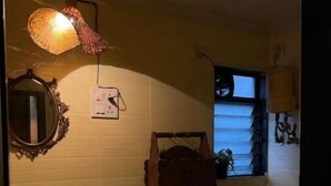 Ett litet badrum med toalett, handfat och dusch. Det finns en spegel, en väggmonterad lampa och ett fönster.