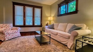 A living room with a floral-patterned armchair, a white sofa, a glass coffee table, and a lamp. - Beautiful 3 bedroom century home steps from uptown (Waterloo)