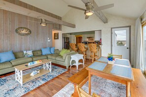 A spacious living room with a wooden ceiling, a green sofa, a wooden dining table, and a kitchen in the background. - Delaware Bay & Sunset Views: Cape May Cottage (Cape May Court House)