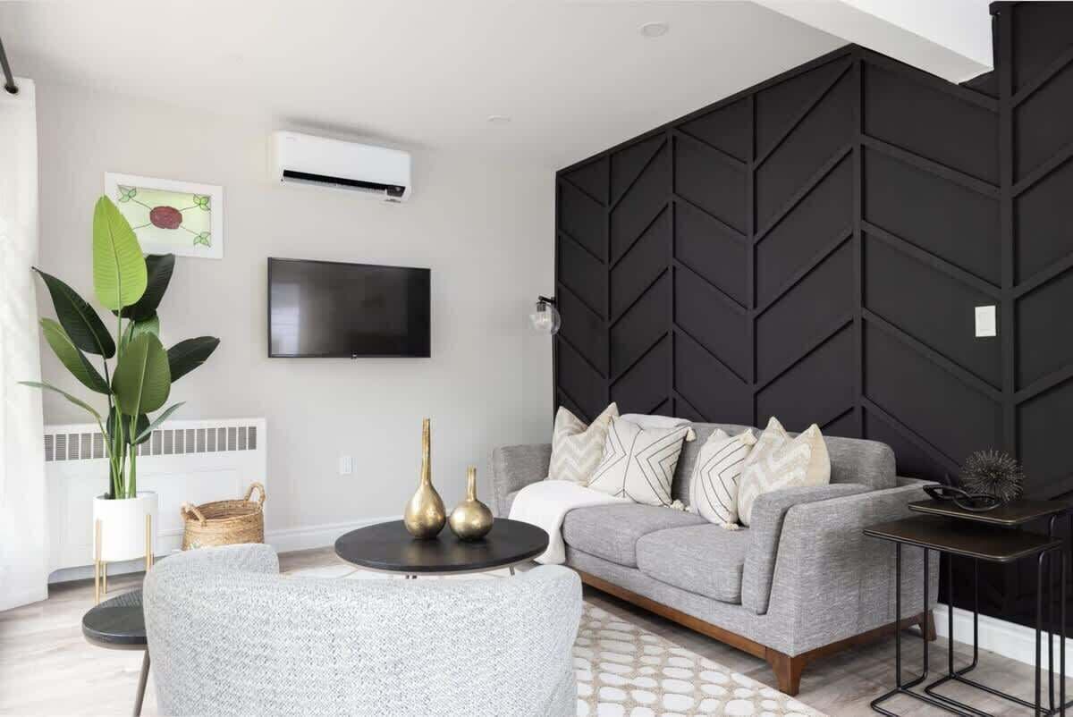 Una sala de estar moderna con un sofá gris, una mesa redonda de centro y una pared de acento negra.