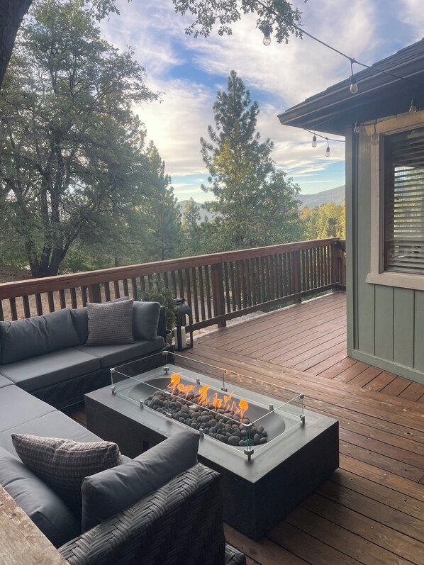 A deck with a fire feature, outdoor seating, and a view of trees and hills. - Large, luxury retreat with National Forest views (Big Bear)