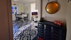 Ein modernes Interieur mit einem gemusterten Boden, einer runden Wandleuchte und einer schwarzen Kommode mit Schubladen.