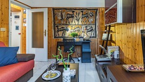 A modern living room with a sofa, a dining table with a vase and plates, a desk with a computer, and a decorative tapestry. - GuestHost - Cozy apartment of 70 sqm, able to accommodate up to 4 people, located on the ground floor of a building with private entrance (two steps to access it).The location is enviable, in the center of Pisa, a few steps from Piazza dei Miracoli and t (Pisa)