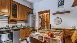 A kitchen with wooden cabinets, a refrigerator, an oven, and a dining table set for a meal. - GuestHost - Cozy apartment of 70 sqm, able to accommodate up to 4 people, located on the ground floor of a building with private entrance (two steps to access it).The location is enviable, in the center of Pisa, a few steps from Piazza dei Miracoli and t (Pisa)