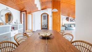 Un comedor con una mesa de madera, sillas de mimbre y un centro decorativo.