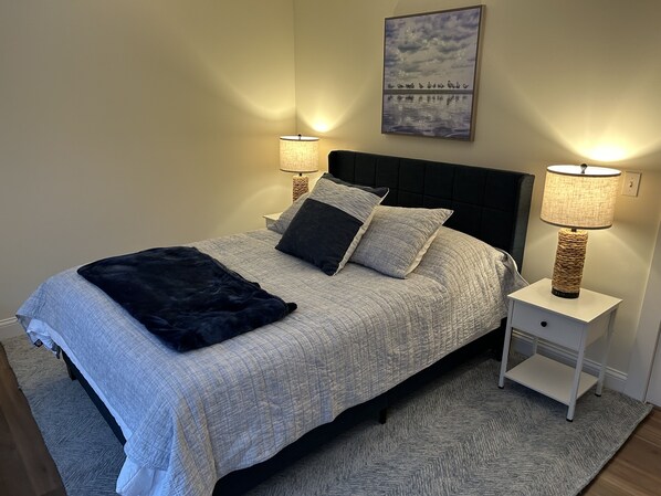 A neatly arranged bedroom with a bed, two bedside tables, and a wall-mounted lamp.