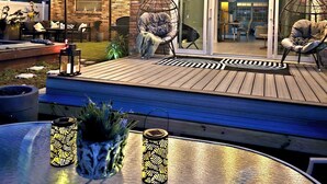 Eine Terrasse im Freien mit Holzdeck, zwei Hängestühlen und einem Tisch mit dekorativen Laternen.
