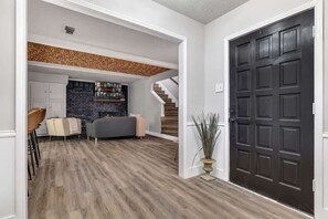 A modern interior with a dark wooden floor, a grey sofa, a white cabinet, and a black door.