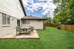 A house with a patio, a small attached garage, and a fenced yard.
