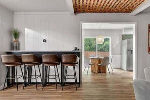 A modern kitchen with a bar area, wooden flooring, and a view of the outdoors.