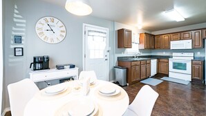 Une cuisine moderne avec des meubles en bois, une cuisinière blanche et une grande horloge murale.
