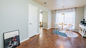 Un espace repas avec une table et des chaises, un coin cuisine avec un comptoir et des appareils électroménagers, et une porte donnant sur une autre pièce.