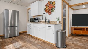 Una cocina moderna con armarios blancos, electrodomésticos de acero inoxidable, encimera de granito y un cuadro decorativo con flores.