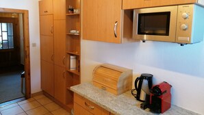 A kitchen with wooden cabinets, a microwave, a coffee maker, and a built-in oven. - Outside: Chalet of about 132m2, for 10 people, with garden and garden furniture -Inside: living room (Chandolin)