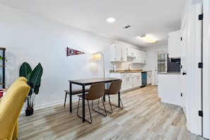 Una cocina moderna con armarios blancos, una mesa de comedor de madera y una silla amarilla.