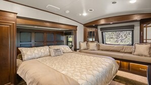 A bedroom with a large bed, a sofa bed, and a window with a view.