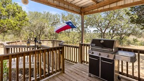 A covered outdoor deck with a grill and a Texas flag.