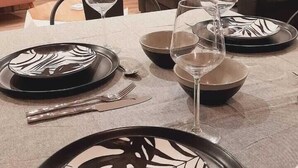 Comedor con una mesa dispuesta para cuatro personas, con platos de diseño blanco y negro y copas de vino.