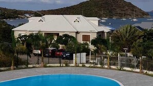 Una piscina con vista a una casa y un paisaje montañoso al fondo.