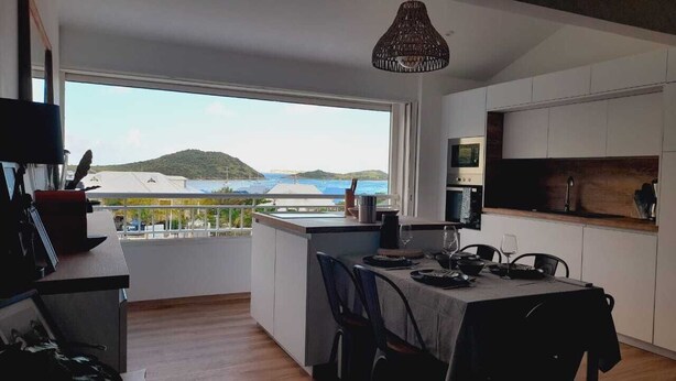 Una cocina moderna con comedor, ventanas amplias con vista al mar y un balcón.