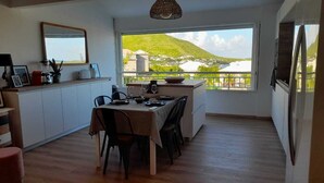Una cocina moderna con comedor, amplios ventanales con vista a un paisaje verde, y una lámpara colgante.