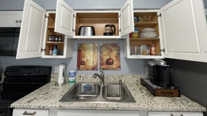 Une cuisine avec deux placards ouverts, un évier et une cuisinière.