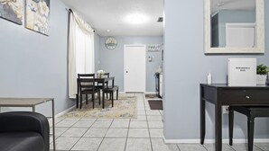 Une pièce comprenant une table à manger, des chaises, un canapé, un petit meuble et un miroir au mur.